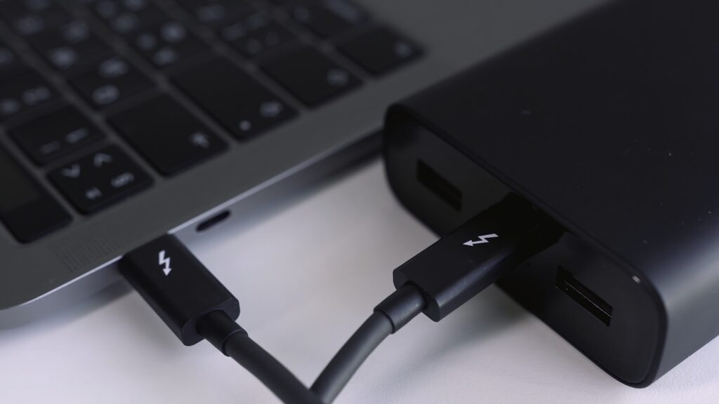 Close up of external hard drive connected to laptop. Action. Black hard disc for backup files and