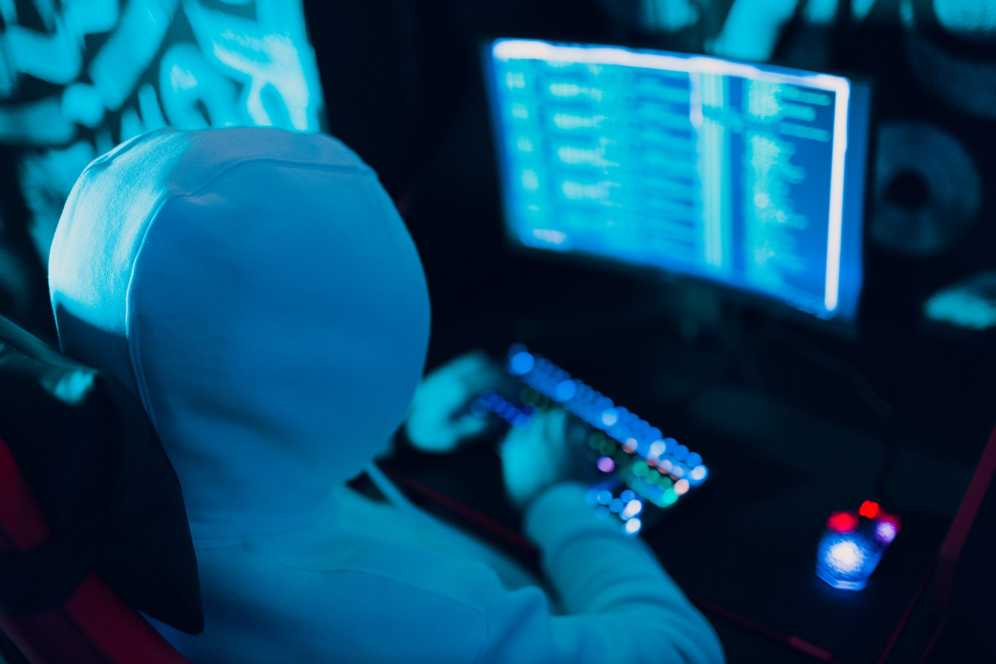Hacker in hoodie working hacks code site on personal computer with keyboard